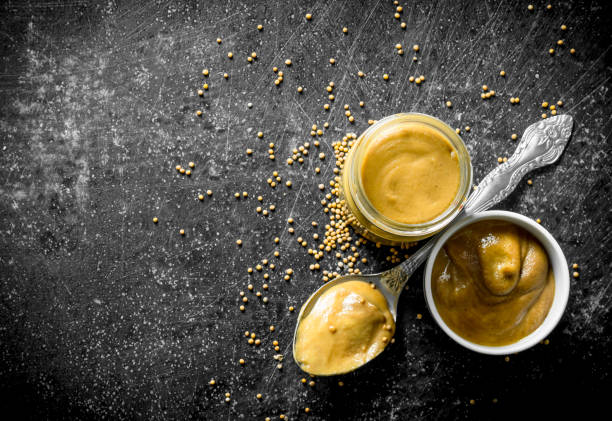 Mustard in a glass jar, spoon and bowl.