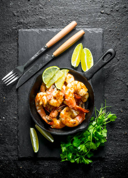 istock Fragrant shrimps on a stone Board with parsley and lime. 1156086820