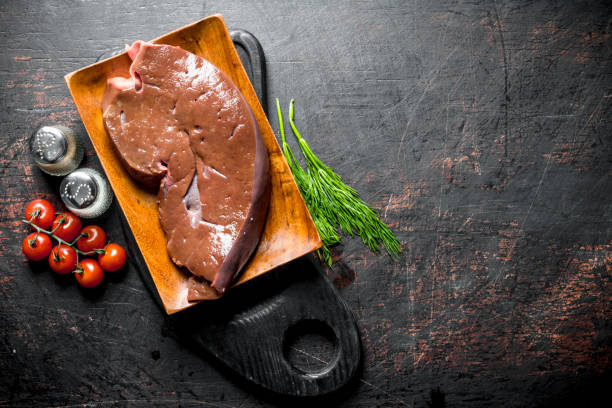 istock Raw liver with herbs, tomatoes and spices on the cutting Board. 1156087402