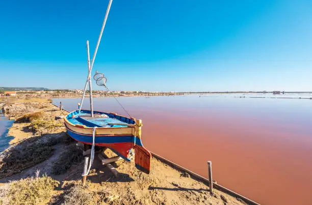 Photo of Saline island of Saint Martin de Gruissans, the old wooden ship at left and the reddish colored saturated with salt water at right.  Occitanie, France.