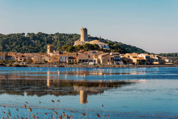 Historical center of Gruissan town with Barberousse Tower in top seen from the opposite side of the pond. Occitanie, France. Historical center of Gruissan town with Barberousse Tower in top seen from the opposite side of the pond. Occitanie, France. narbonne stock pictures, royalty-free photos & images