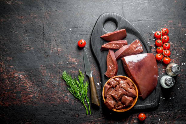 istock Raw liver with cherry tomatoes, spices and dill on a cutting Board. 1156087864