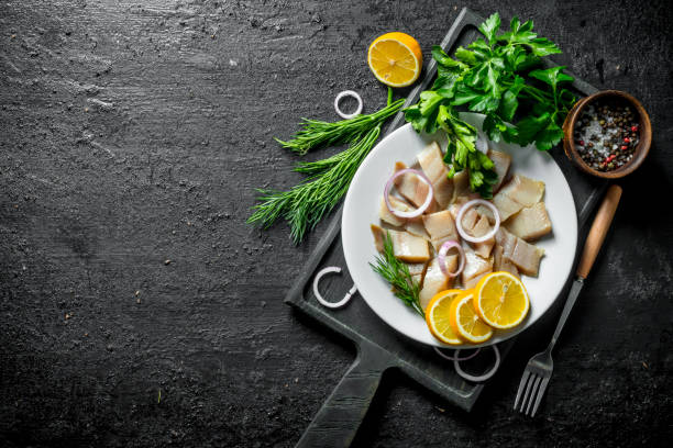 istock Pieces of salted herring with herbs, spices and lemon. 1156090592