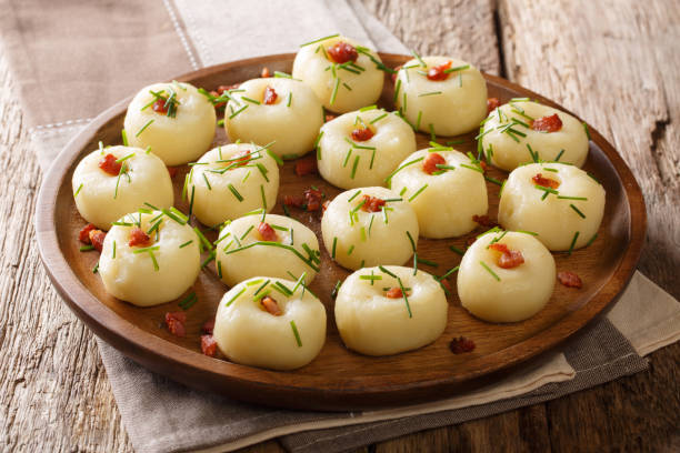 istock Boiled potato dumplings with fried bacon and fresh green onions close-up on a plate. horizontal 1156090643