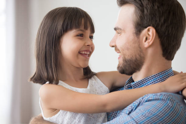 istock Smiling dad hold daughter in arms laughing together 1156092055