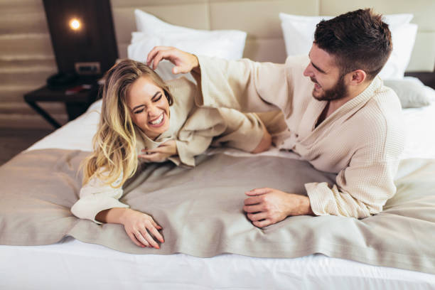 młoda kochająca para w szlafrokach relaksująca się na łóżku w hotelu - bathrobe health spa spa treatment couple zdjęcia i obrazy z banku zdjęć