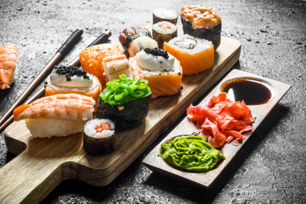 istock Sushi rolls with salmon and vegetables on a cutting Board with sauce and chopsticks. 1156093502