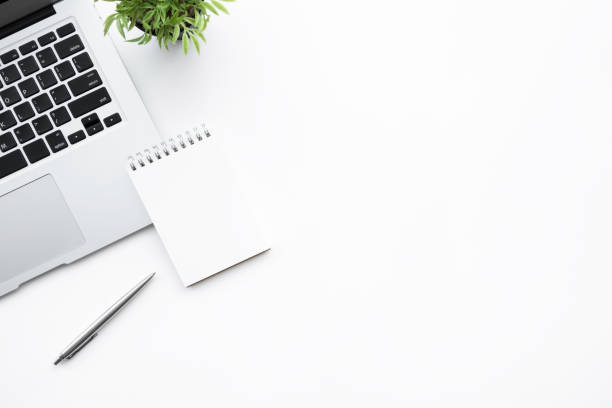 istock White office desk table with laptop computer, blank notebook and pen. Top view with copy space, flat lay. 1156093985