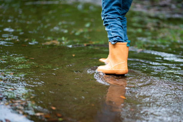 istock Children's feet playing in a puddle 1156100123
