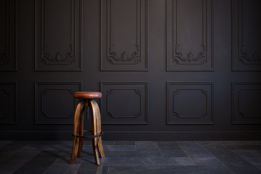 high bar stool against a dark gray wall. Stylish wooden chair in loft style, in classic interior