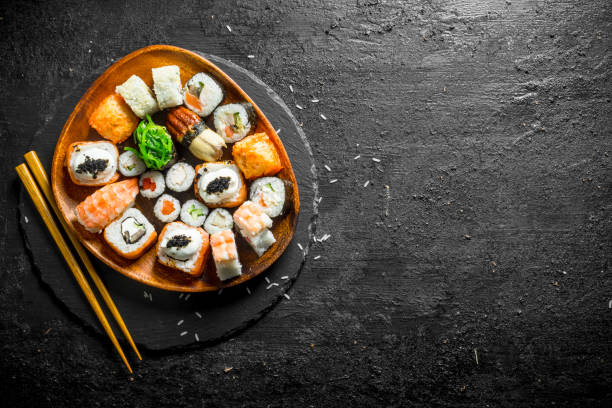 istock Assortment of different sushi rolls on a plate with chopsticks. 1156103592