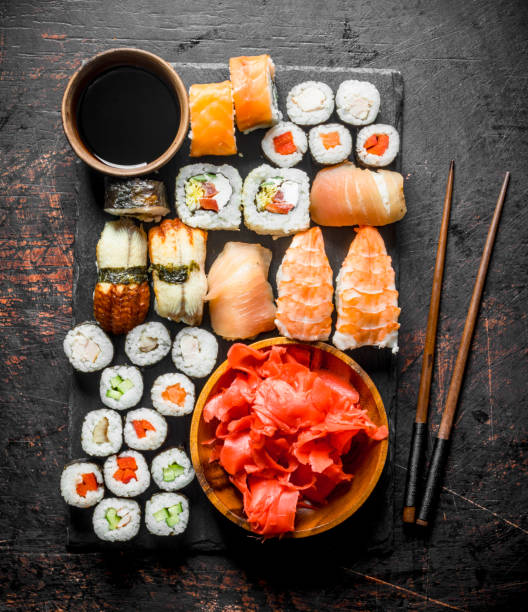 Various rolls, sushi and maki on a stone Board with soy sauce and ginger. Various rolls, sushi and maki on a stone Board with soy sauce and ginger. On dark rustic background food state preparation shrimp prepared shrimp stock pictures, royalty-free photos & images