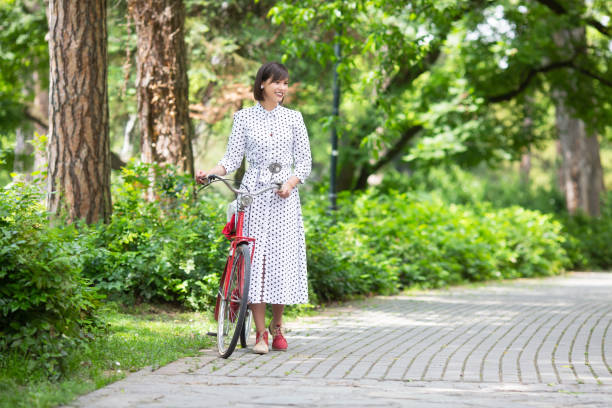 istock Young woman with bicycle in park 1156106579