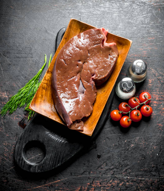 istock Raw liver with herbs, tomatoes and spices on the cutting Board. 1156106966