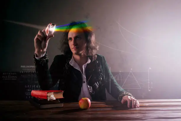 Physics the science of nature, the concept of studying the laws of nature. A young man in the image of Isaac Newton. Looks at the prism, the science of light, optics