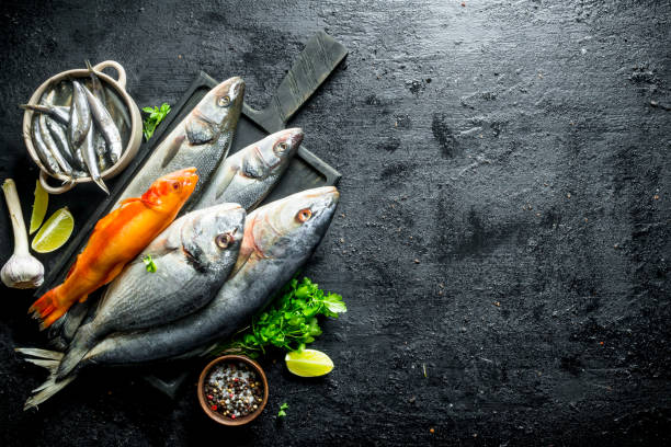 istock Various fresh fish on a cutting Board with spices, parsley, garlic and lime. 1156108650