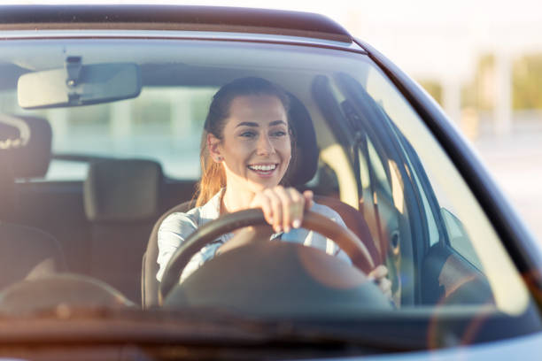 Woman driving car in the sunset Happy woman driving a car and smiling carsharing photos stock pictures, royalty-free photos & images