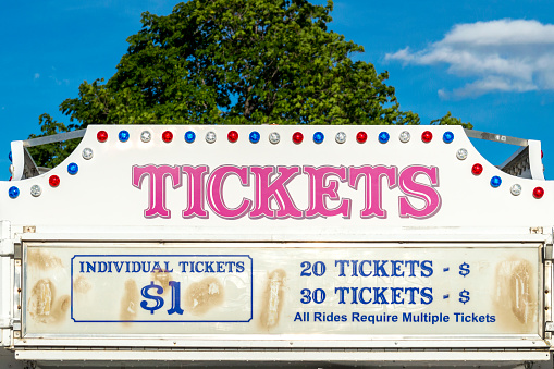 This booth sells tickets at a traveling carnival.  The lights and signage advertise tickets for sale and the price of each ticket.