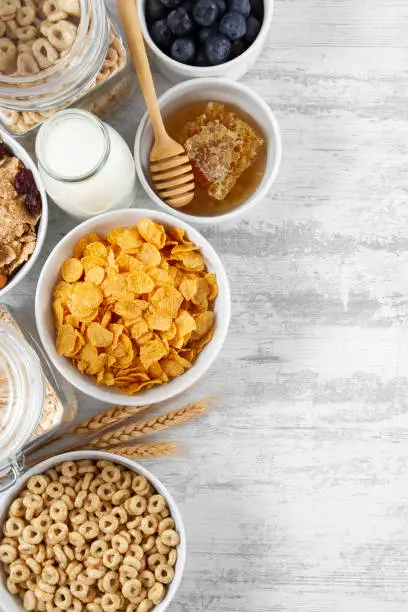 Cornflakes and breakfast cereals with fresh berries and honey on white wooden table