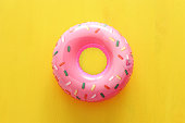 Inflatable donut ring over yellow wooden background