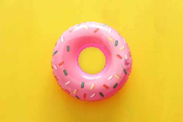 Photo of Inflatable donut ring over yellow wooden background