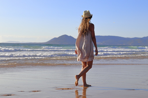 Teenage girl standing on a cliff and looking at the sea