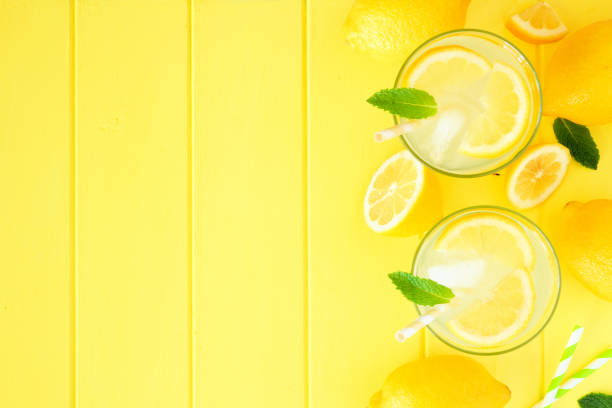 istock Summer lemonade, top view side border on a bright yellow wood background 1156127655