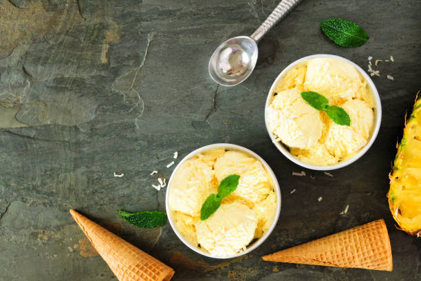 istock Two bowls of pineapple ice cream, corner border over a slate background 1156128765