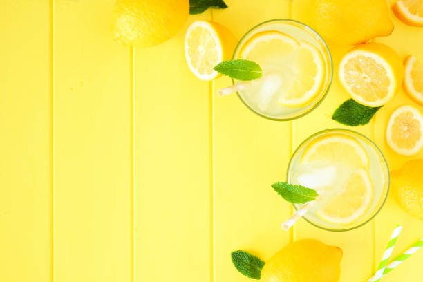 istock Summer lemonade top view corner border on a yellow wood background 1156128946