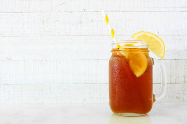 iced tea in a mason jar glass, side view against white wood - chá gelado imagens e fotografias de stock