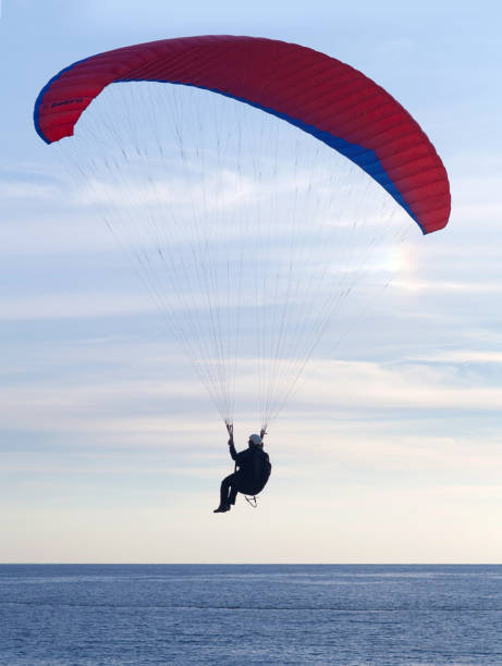 paralotnia lecący o zachodzie słońca nad błękitną laguną w oludeniz, turcja - skydiving air aerial view vertical zdjęcia i obrazy z banku zdjęć