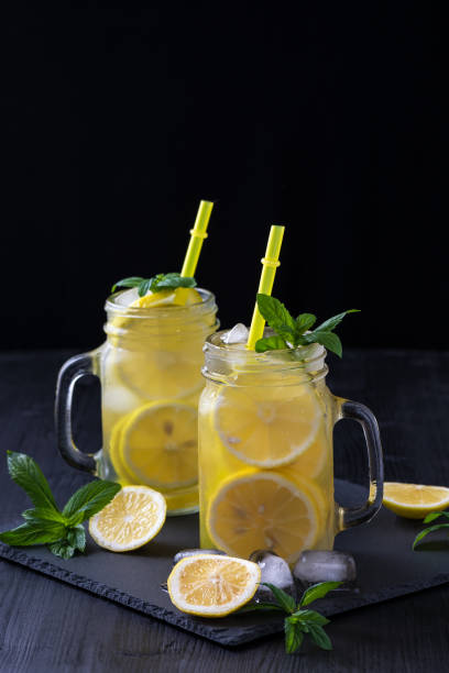 istock Lemonade in a jar with ice and mint on a black wooden table. 1156129893