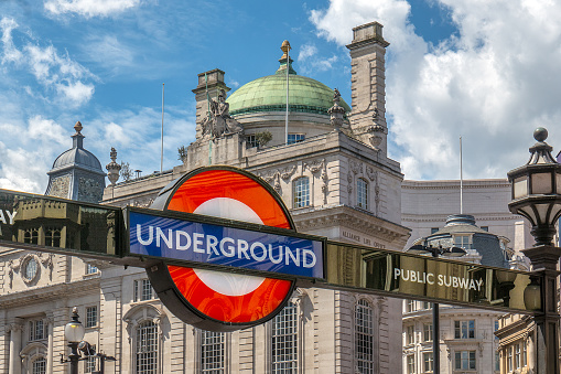 Sign of the London subway at Piccadilly Circus, London, England. In the background some buildings
