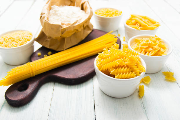 istock Raw pasta piles on white wooden table 1156130060