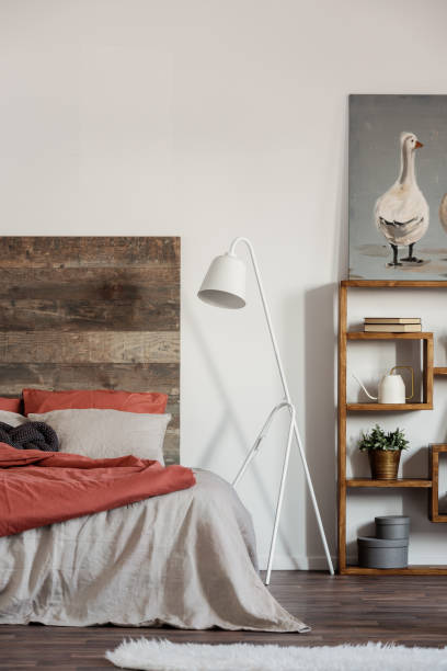 istock Comfortable king size bed with wooden rustic headboard and white industrial lamp next to it 1156140407