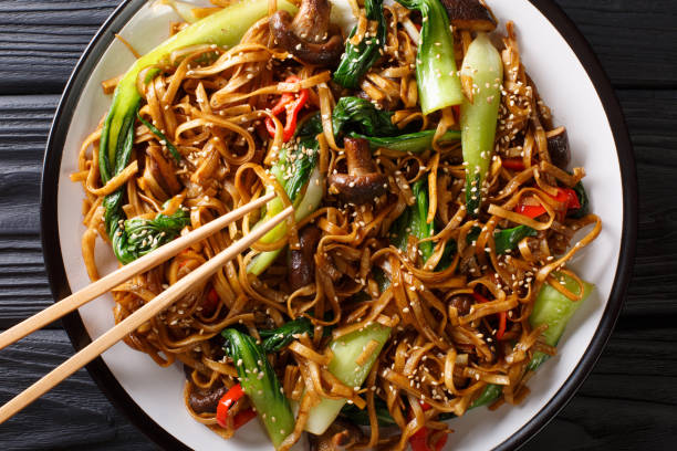 stir fry of udon noodles with pak choi and shiitake mushrooms close-up. horizontal top view - main course imagens e fotografias de stock