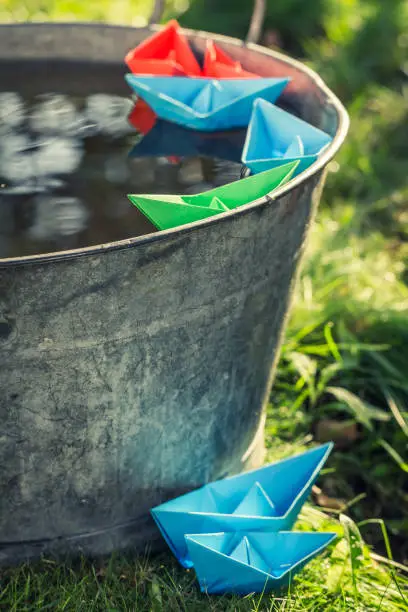 Photo of Closeup of paper boats floating on water in washtube