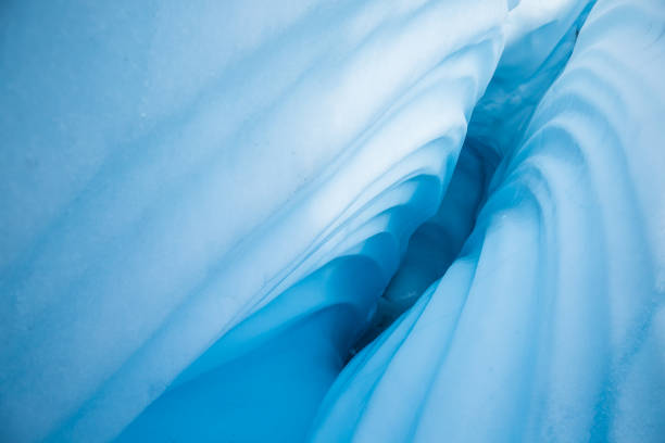 A deep crevasse on the Matanuska Glacier in Alaska. The sides have a wavy texture from water running through and melting a hole in the ice.