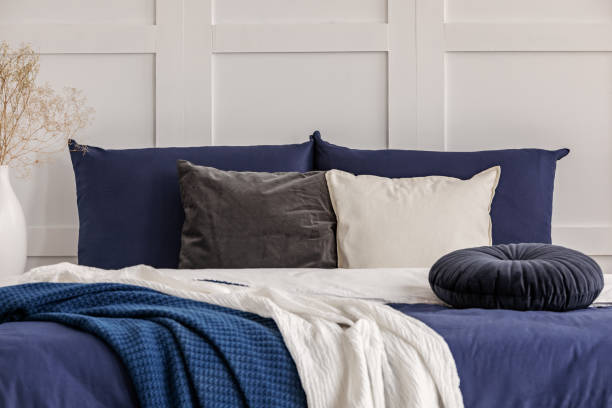 istock Velvet round pillow on king size bed with blue and white sheets 1156144918