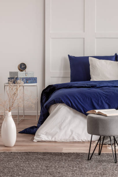 istock Open book on grey pouf in trendy bedroom interior with blue and white design 1156144922