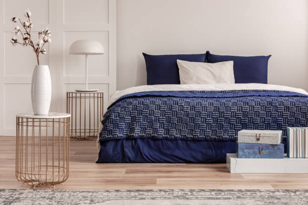 istock Flowers in vase on bedside table next to king size bed with navy blue bedding 1156144924