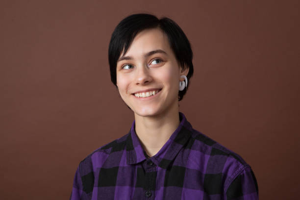 studio portrait of an attractive 18 year old woman with short hair on a brown background. - earring human face brown hair black hair imagens e fotografias de stock