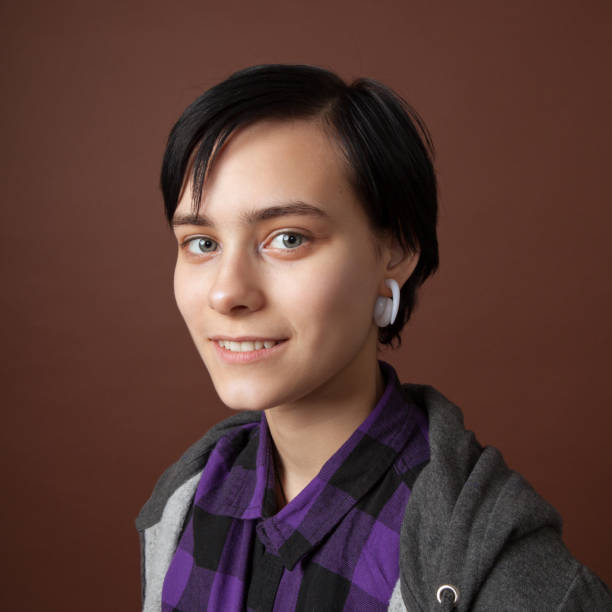 studio portrait of an attractive 18 year old woman with short hair on a brown background. - earring human face brown hair black hair imagens e fotografias de stock