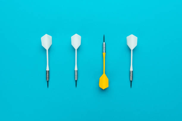 conceptual image of yellow dart pointing to other direction on blue background - individuality standing out from the crowd contrasts competition imagens e fotografias de stock