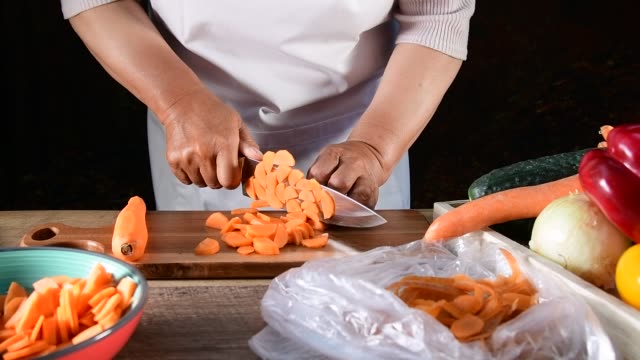woman cuts  carrot with a knife at a kitchen