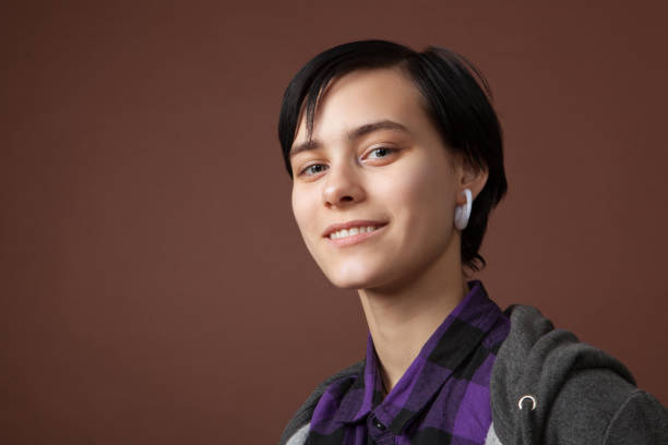 studio portrait of an attractive 18 year old woman with short hair on a brown background. - earring human face brown hair black hair imagens e fotografias de stock