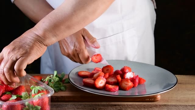 Close-up of woman hand cutting strawberries