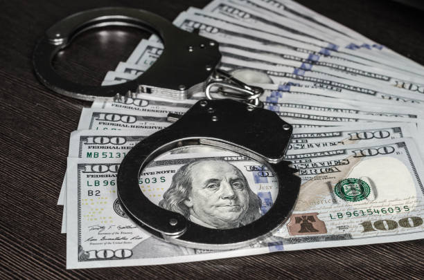 one hundred dollar bills and steel handcuffs close up one hundred dollar bills and steel handcuffs closeup bail bond services stock pictures, royalty-free photos & images