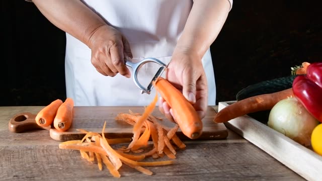 Woman hands peel fresh carrot