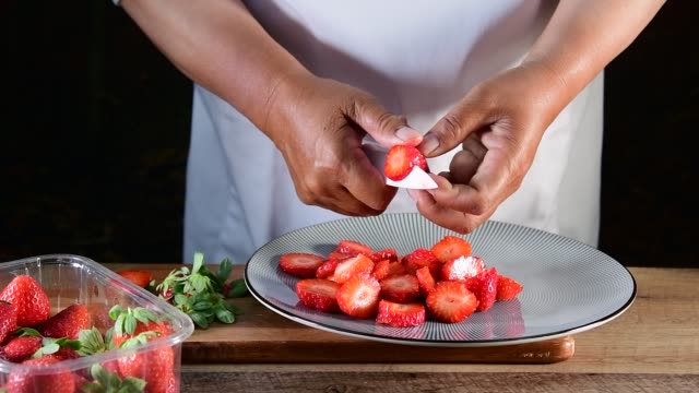 Woman hand cutting fresh strawberries sliced with a knife